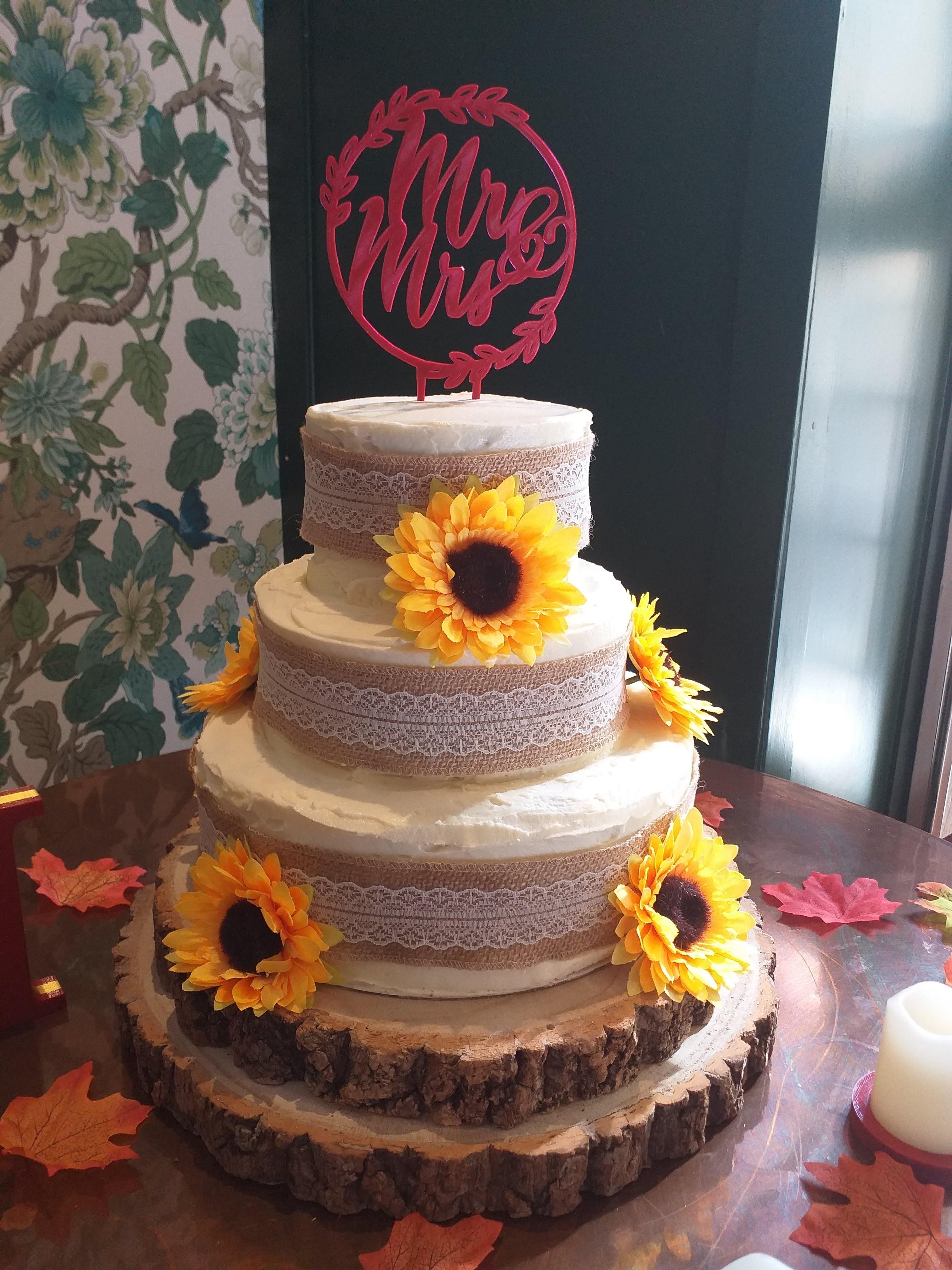 A gorgeous three tiered wedding cake with sunflower decoration.